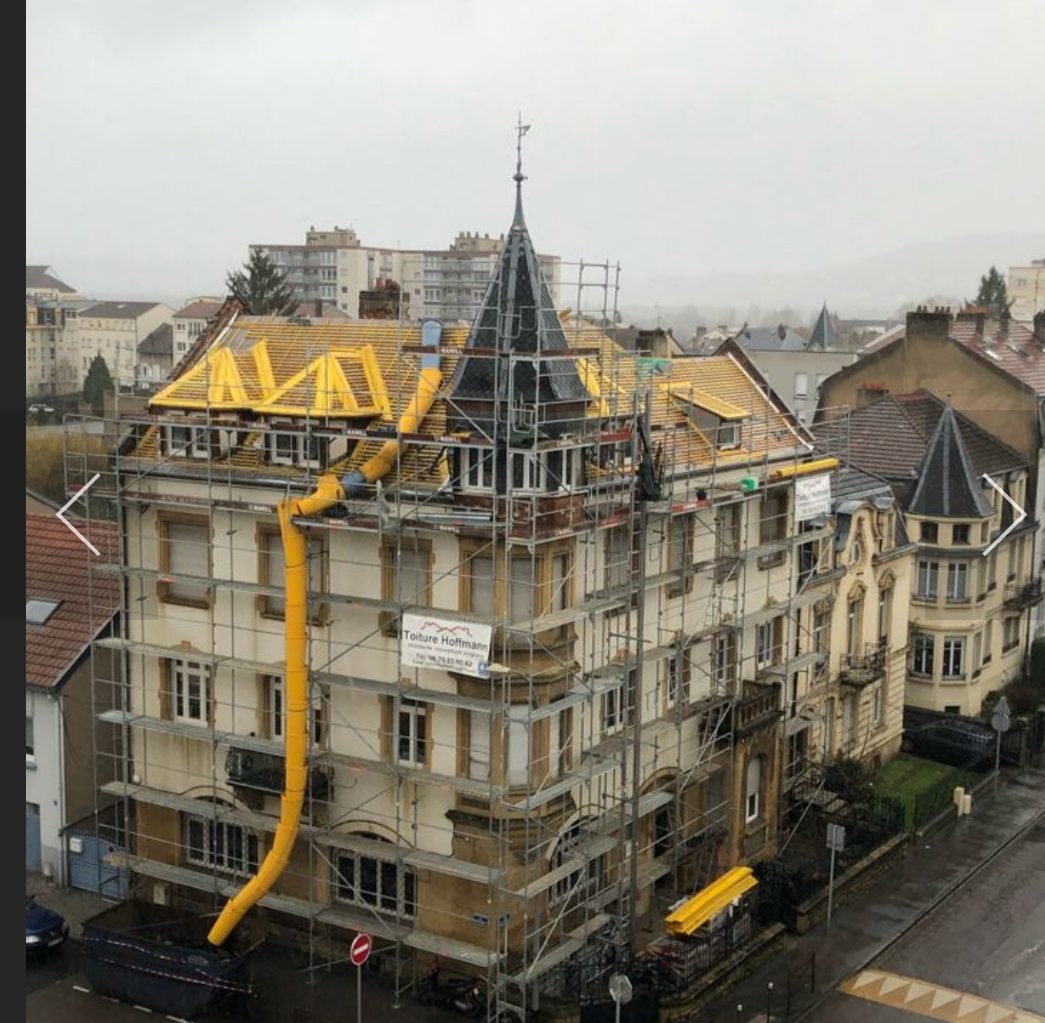 Chantier de toiture d'un immeuble, entièrement sous échafaudage